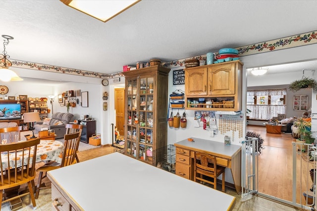 kitchen with a textured ceiling, hanging light fixtures, and light hardwood / wood-style flooring