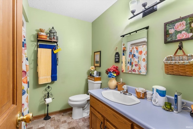 bathroom featuring a textured ceiling, vanity, and toilet