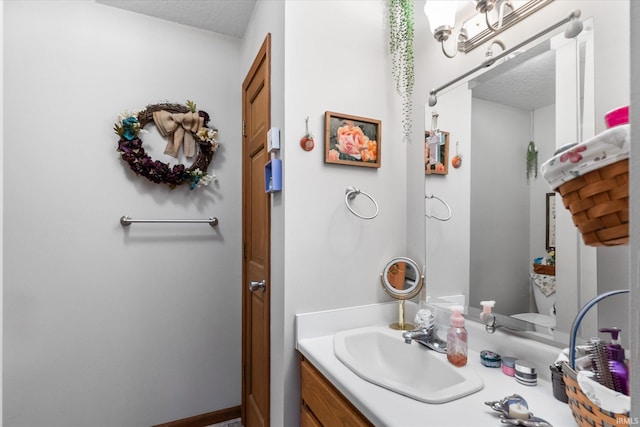 bathroom featuring vanity, a textured ceiling, and toilet