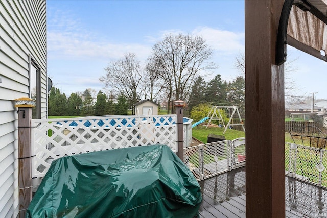 wooden terrace with a playground and a grill