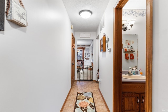 corridor with sink and a textured ceiling