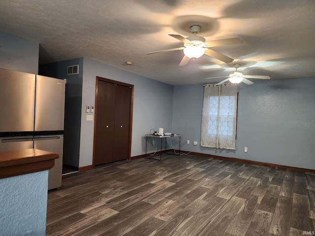 unfurnished room featuring a textured ceiling, ceiling fan, and dark wood-type flooring