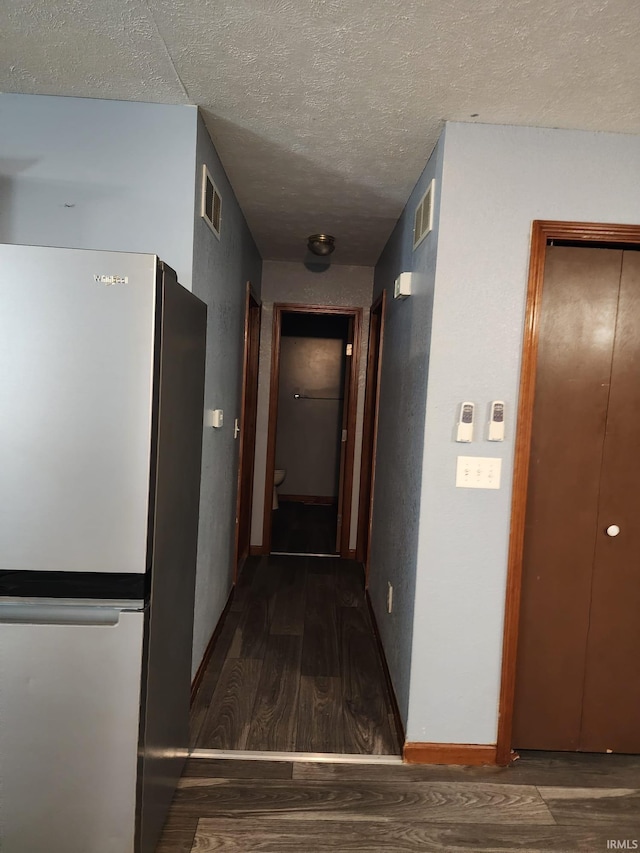 hallway with a textured ceiling and dark wood-type flooring