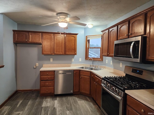 kitchen featuring dark wood-type flooring, sink, ceiling fan, a textured ceiling, and appliances with stainless steel finishes