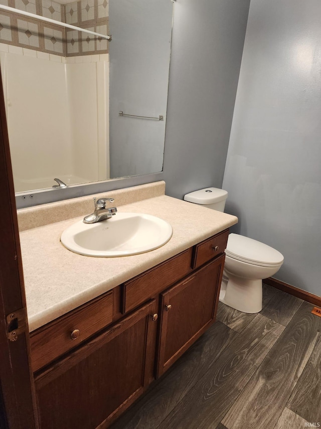 bathroom featuring a shower, toilet, vanity, and hardwood / wood-style flooring