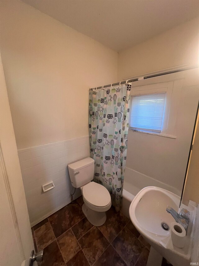 bathroom featuring tile walls, shower / bath combo, and toilet