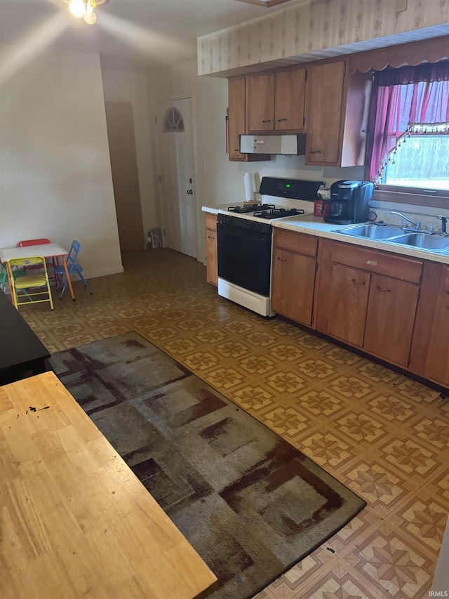 kitchen with exhaust hood, white gas range, and sink