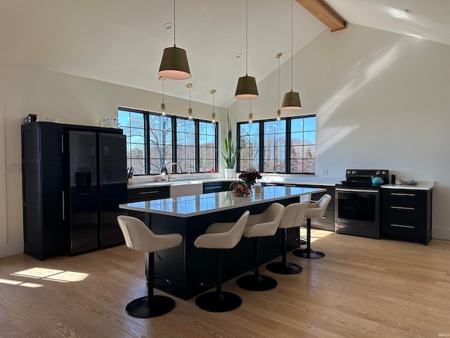 kitchen featuring a breakfast bar area, hanging light fixtures, stainless steel range with electric stovetop, and light hardwood / wood-style floors