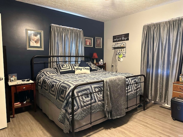 bedroom with a textured ceiling and light wood-type flooring