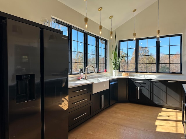 kitchen with vaulted ceiling, sink, pendant lighting, fridge with ice dispenser, and light hardwood / wood-style floors