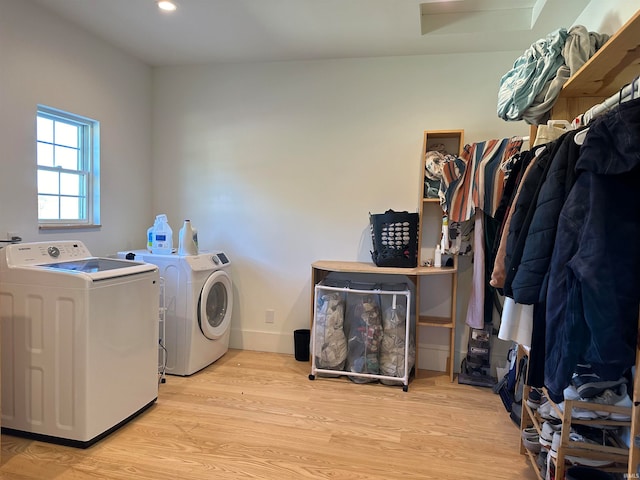 clothes washing area with light hardwood / wood-style flooring and washer and clothes dryer