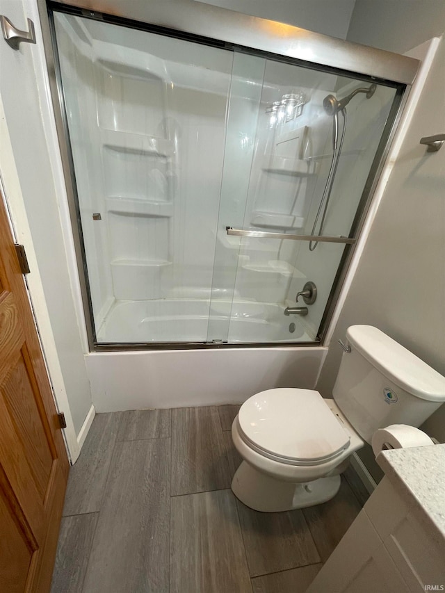 bathroom with toilet, enclosed tub / shower combo, and hardwood / wood-style flooring