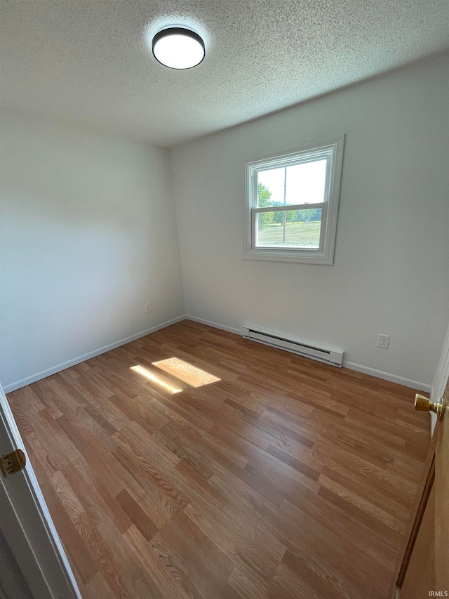 unfurnished room featuring a baseboard radiator, a textured ceiling, and light wood-type flooring