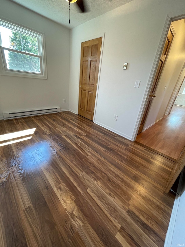 unfurnished bedroom featuring ceiling fan, dark wood-type flooring, a baseboard radiator, and a textured ceiling