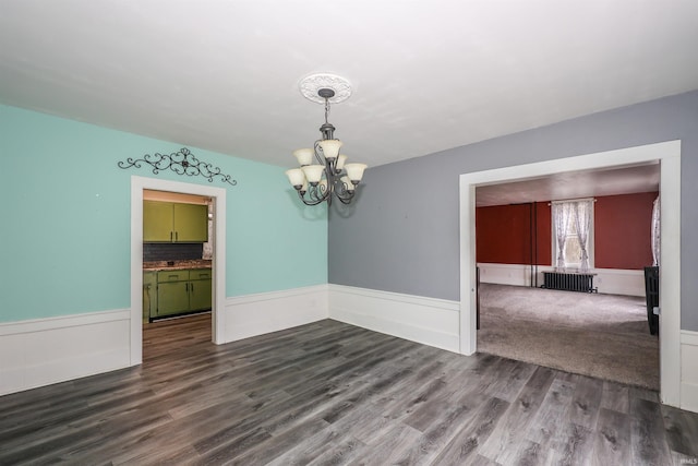 interior space with a chandelier, wood-type flooring, and radiator heating unit