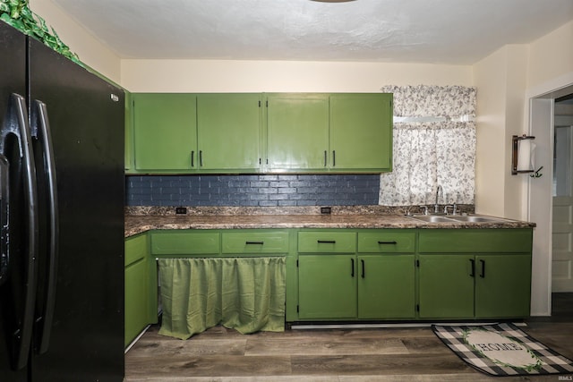 kitchen with black refrigerator, decorative backsplash, sink, green cabinetry, and dark hardwood / wood-style floors