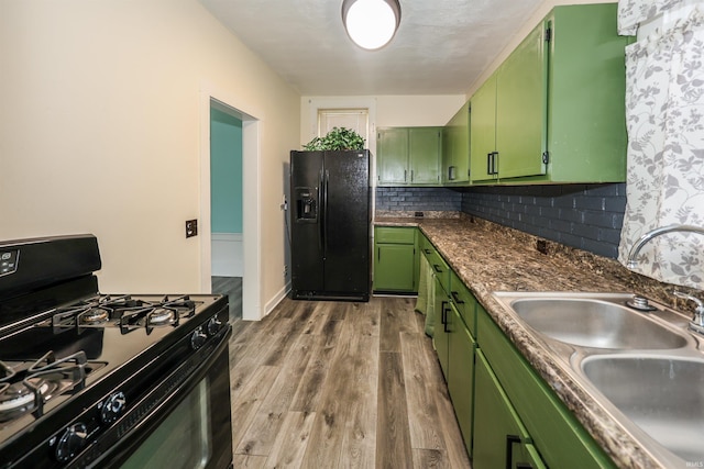 kitchen featuring sink, tasteful backsplash, green cabinetry, black appliances, and light wood-type flooring