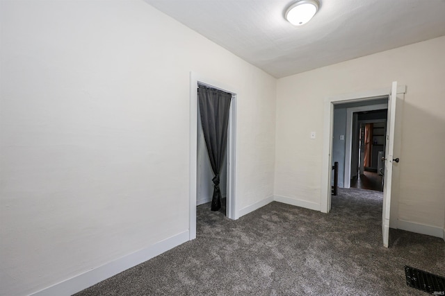 unfurnished room with dark carpet