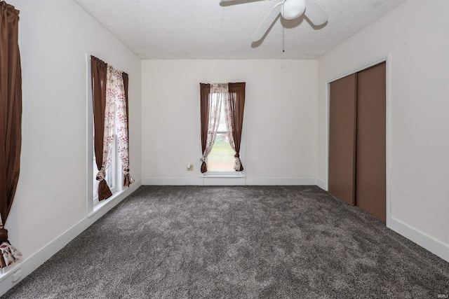 unfurnished bedroom with ceiling fan, dark carpet, and a textured ceiling