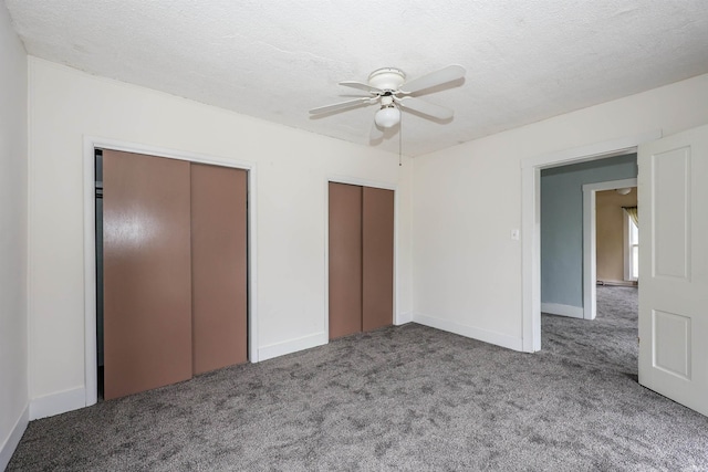 unfurnished bedroom featuring carpet flooring, ceiling fan, a textured ceiling, and two closets