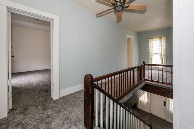 corridor with a textured ceiling and dark carpet