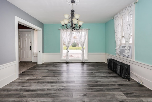 unfurnished dining area featuring dark hardwood / wood-style floors, radiator, and a notable chandelier