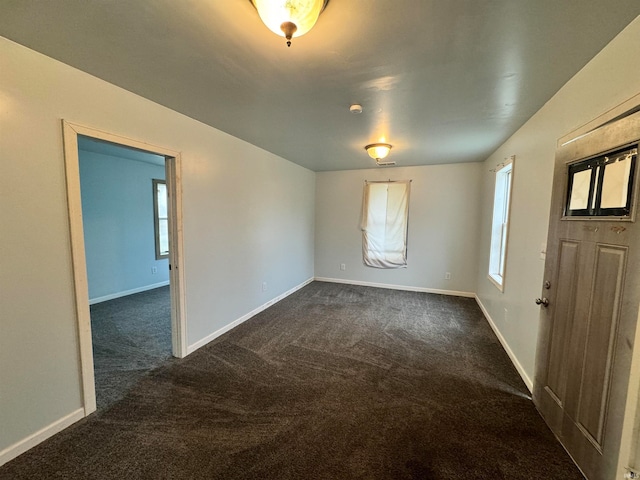 unfurnished room with dark colored carpet