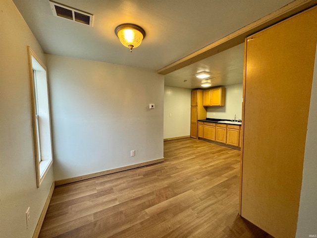 unfurnished living room with light hardwood / wood-style flooring and sink