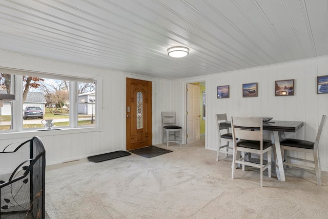 dining space with wood walls and light carpet