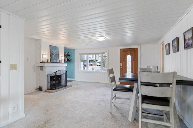 dining room with carpet flooring, crown molding, and a fireplace