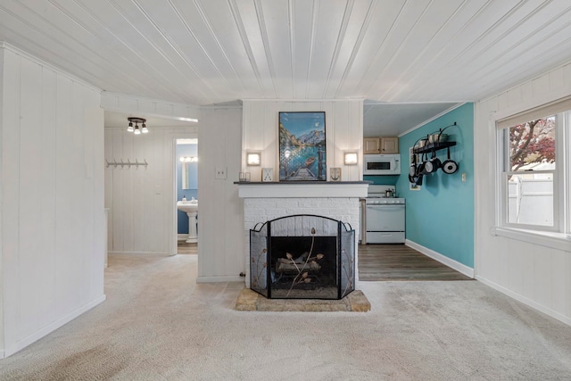 unfurnished living room featuring carpet, wood walls, wooden ceiling, sink, and a brick fireplace