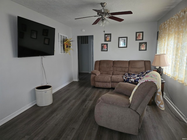 living room with a textured ceiling, ceiling fan, and dark wood-type flooring