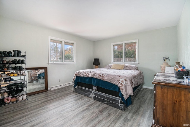 bedroom with wood-type flooring, multiple windows, and a baseboard heating unit