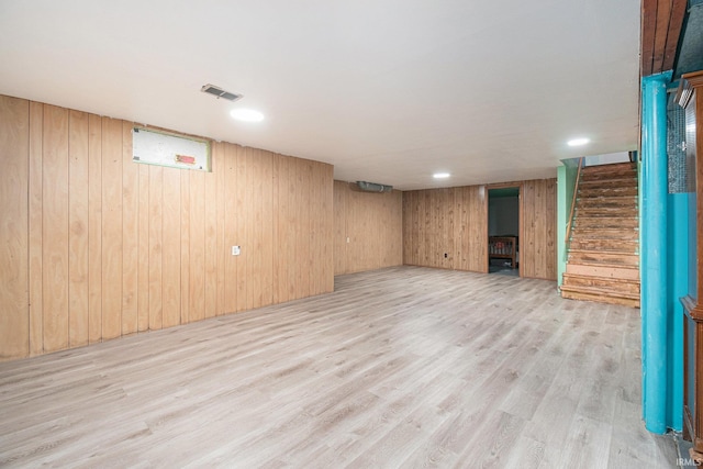 basement featuring wood walls and light hardwood / wood-style floors