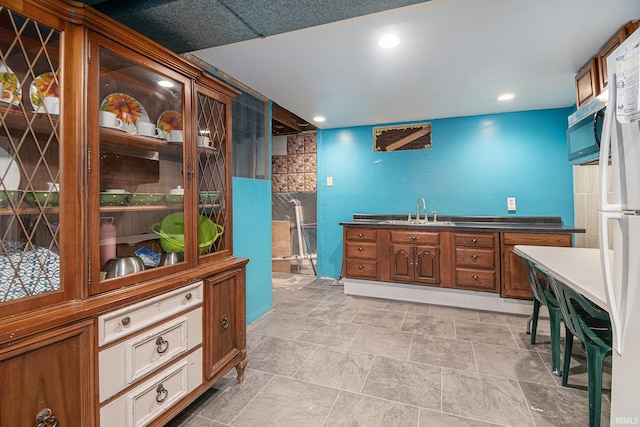 kitchen featuring light tile patterned floors, white refrigerator, and sink