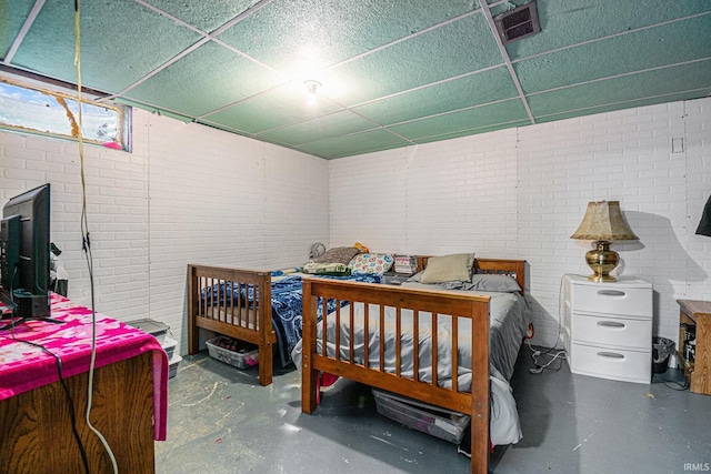 bedroom featuring concrete flooring and brick wall