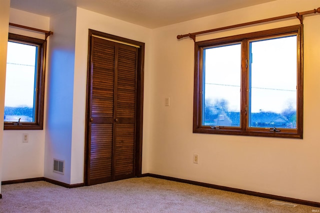 unfurnished bedroom featuring light carpet and a closet