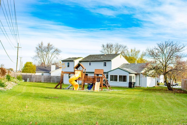 back of property with a yard and a playground