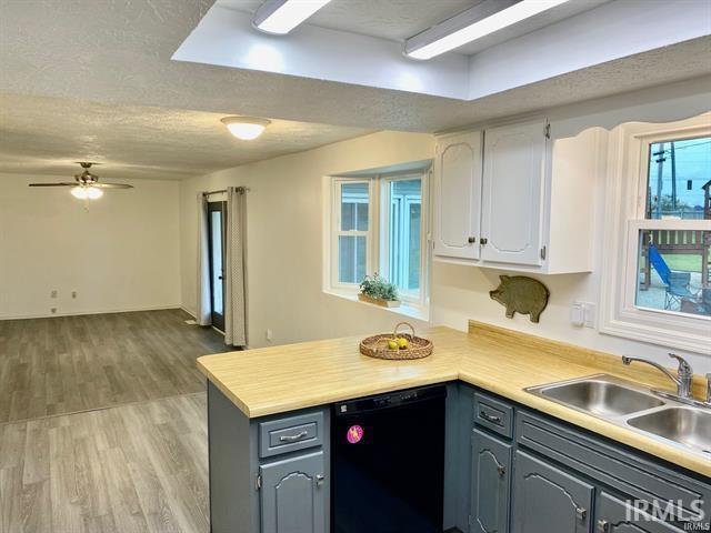 kitchen with kitchen peninsula, white cabinets, sink, dishwasher, and light hardwood / wood-style floors