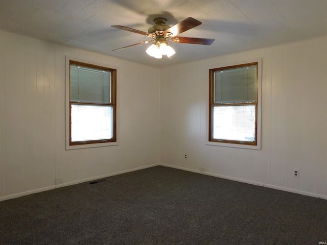 unfurnished room with ceiling fan, plenty of natural light, and dark carpet