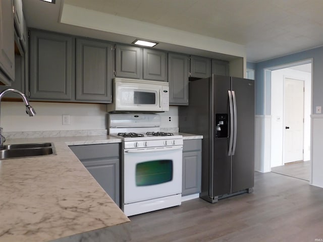 kitchen with gray cabinets, sink, white appliances, and hardwood / wood-style flooring