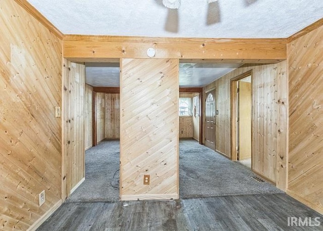 interior space featuring a textured ceiling, dark hardwood / wood-style flooring, and wooden walls