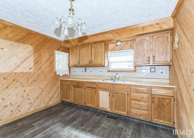 kitchen featuring sink, hanging light fixtures, dark hardwood / wood-style flooring, wood walls, and decorative backsplash