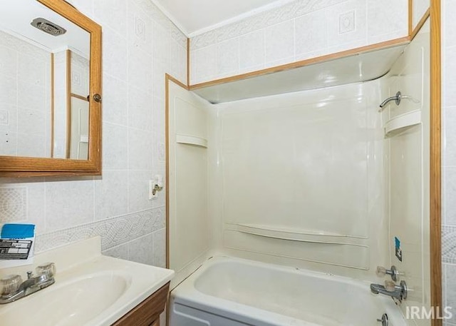 bathroom with washtub / shower combination, vanity, and tile walls