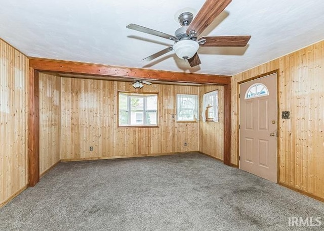 carpeted empty room featuring ceiling fan and wooden walls