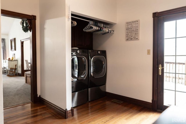 clothes washing area featuring washer and dryer, dark hardwood / wood-style flooring, and cabinets