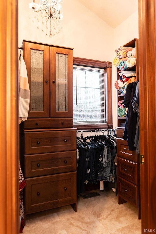 spacious closet featuring a notable chandelier and vaulted ceiling