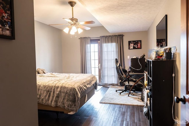 bedroom with a textured ceiling, ceiling fan, and dark wood-type flooring