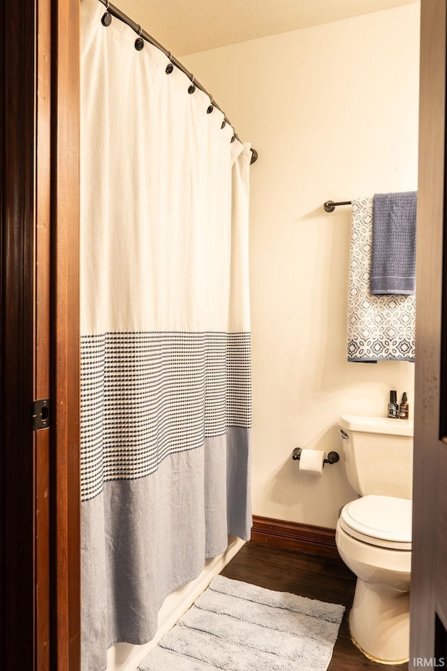 bathroom with a textured ceiling, hardwood / wood-style flooring, and toilet