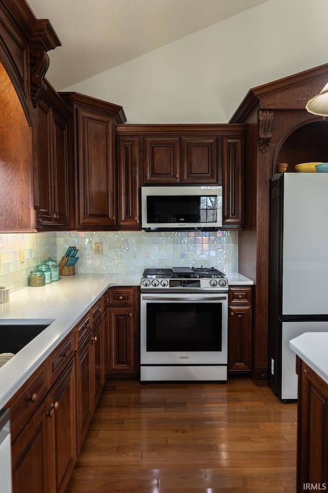 kitchen with decorative backsplash, dark hardwood / wood-style flooring, lofted ceiling, and appliances with stainless steel finishes